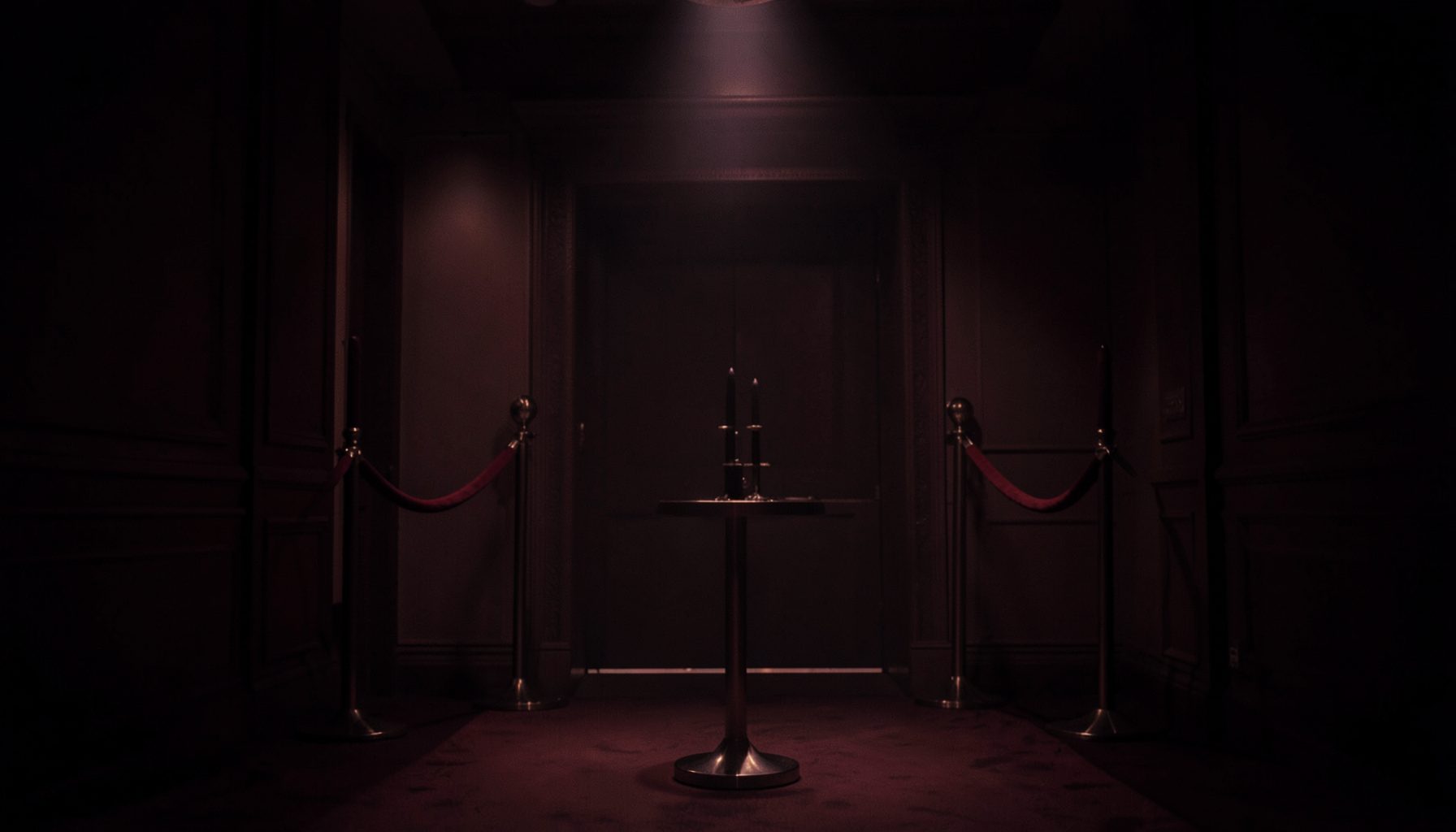 A dark atmospheric scene with deep red and charcoal tones, soft spotlight glow, and a subtle velvet-roped VIP entrance feel