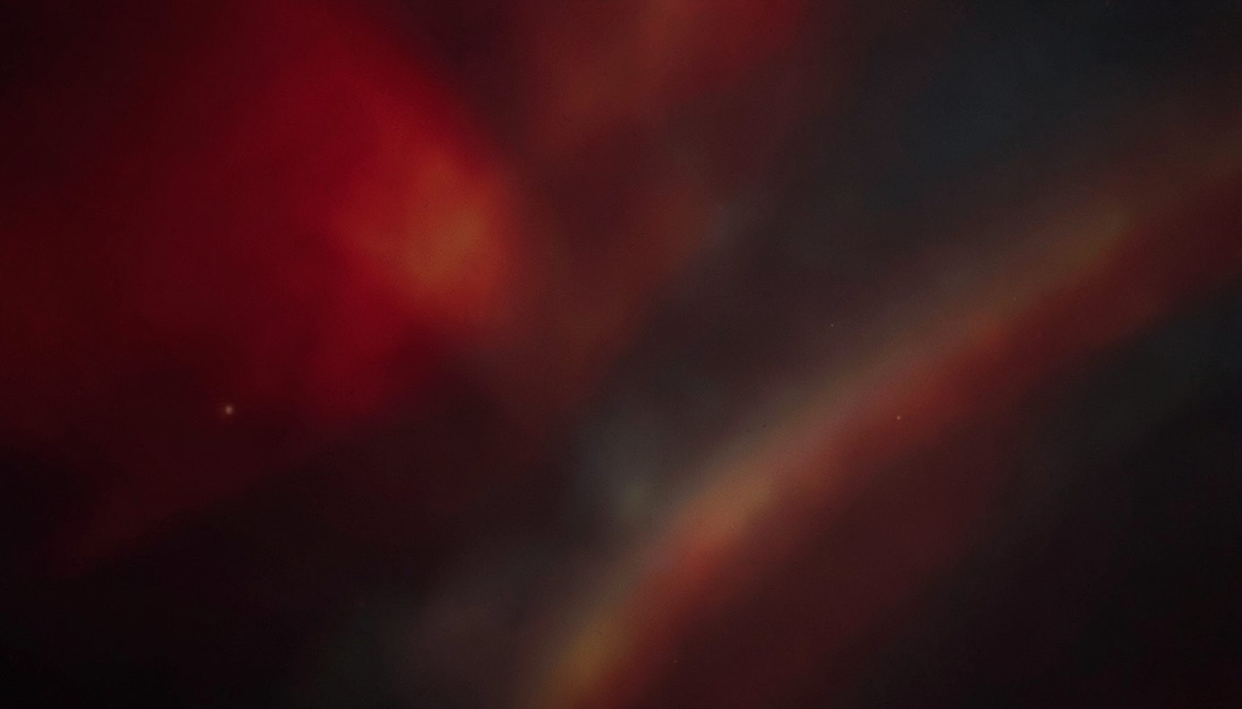 A warm abstract composition of deep crimson and charcoal tones with soft golden highlights, suggesting connection and creative energy.