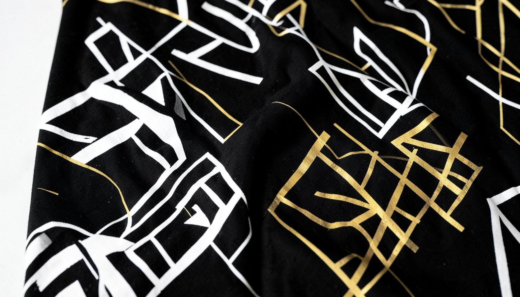 Bold graphic prints on black fabric, with abstract geometric patterns in white and gold.